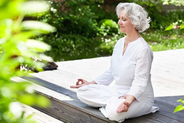 Seniorin macht Yoga im sommerlichen Garten Seniorin macht Yoga im sommerlichen Garten