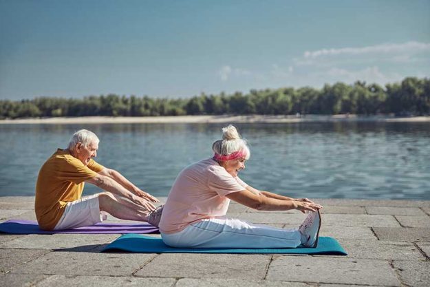 Two senior beginner yogis performing a stretching exercise Two senior beginner yogis performing a stretching exercise