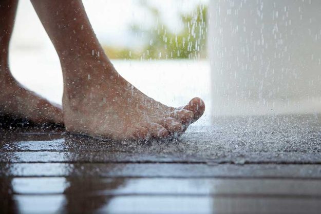 Low section of a woman’s feet under shower Low section of a woman's feet under shower