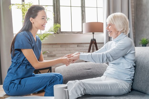 Female caregiver holding elderly woman's hands