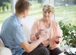Man giving medications to older woman