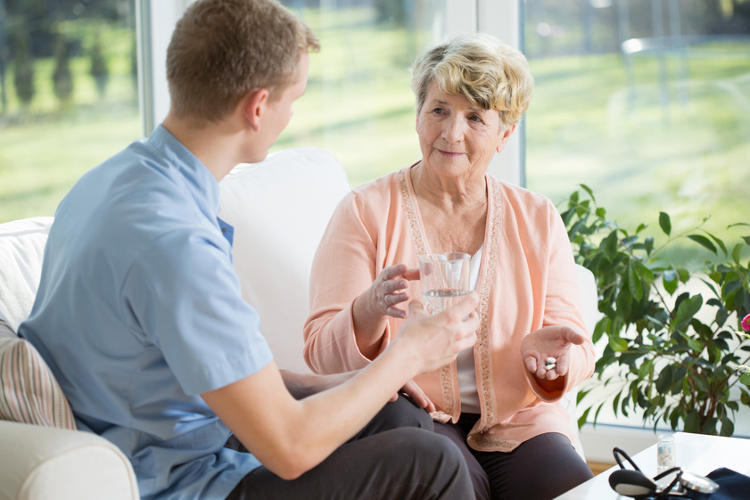 Man giving medications to older woman Man giving medications to older woman