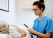 ttractive nurse with eyeglasses sitting in front of woman patient