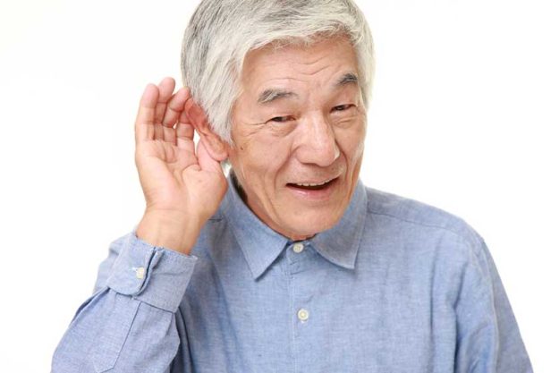 senior Japanese man with hand behind ear listening closely