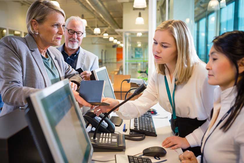 Staff Looking At Passport Held By Businesswoman At Airport Staff Looking At Passport Held By Businesswoman At Airport