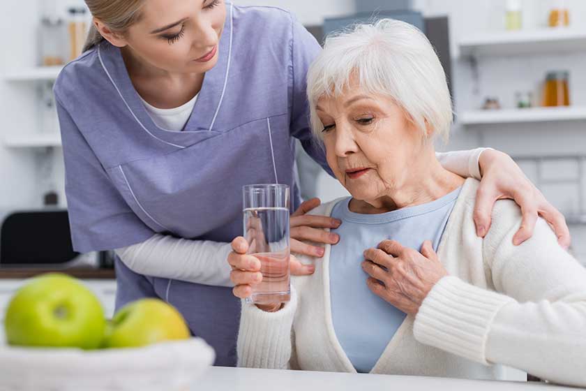 Social worker hugging shoulders of aged woman holdingholding-glass-water-touching Social worker hugging shoulders of aged woman holdingholding-glass-water-touching