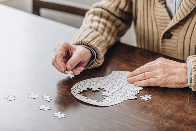 Cropped view of senior man playing with puzzles Cropped view of senior man playing with puzzles