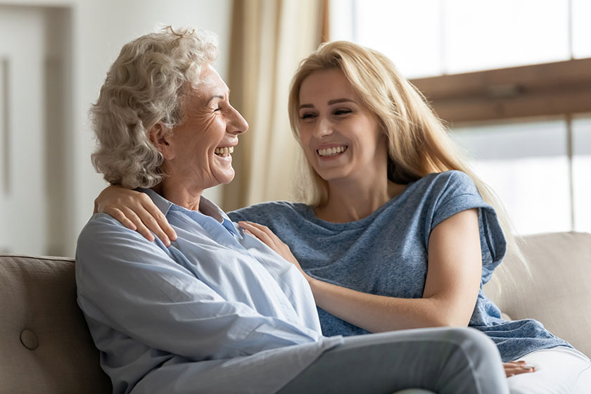 Happy young woman embracing shoulders of excited middle aged mother.