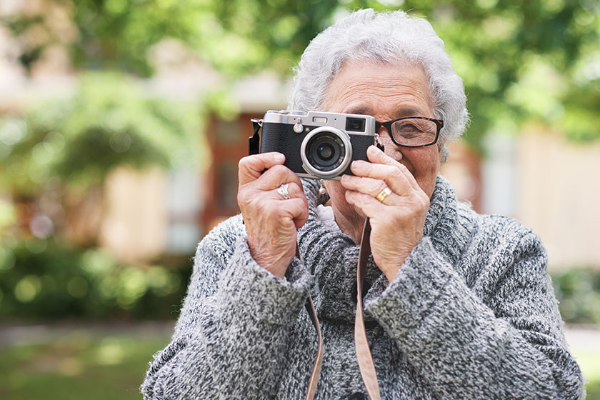 Retirement, relax and elderly woman with photographer hobby to enjoy pension leisure in garden. Satisfied, focused and senior lady with camera busy with nature photography outside nursing home