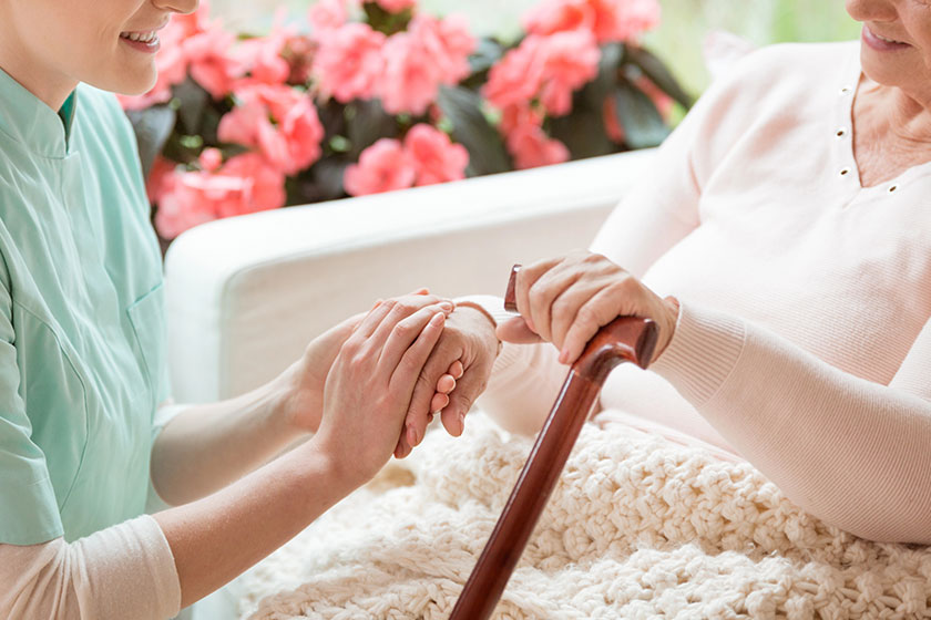 Closeup of a caring volunteer working in a retirement home holding a senior, disabled woman’s hand Closeup of a caring volunteer working in a retirement home holding a senior, disabled woman's hand
