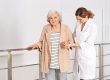 Elderly woman with female caregiver in bedroom.