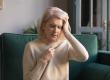 mature-woman-sit-on-couch-touches-head-feels-unhealthy
