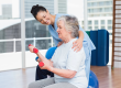 Trainer looking at woman lifting dumbbells