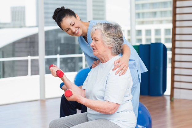 Trainer looking at woman lifting dumbbells