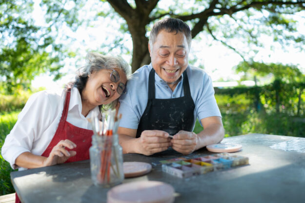 In the pottery workshop, an Asian retired couple is engaged in p